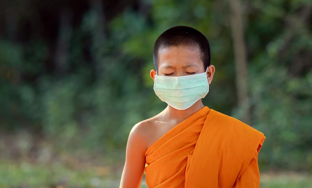 Novice wearing mask meditation under a tree in the temple with lifestyle new normal